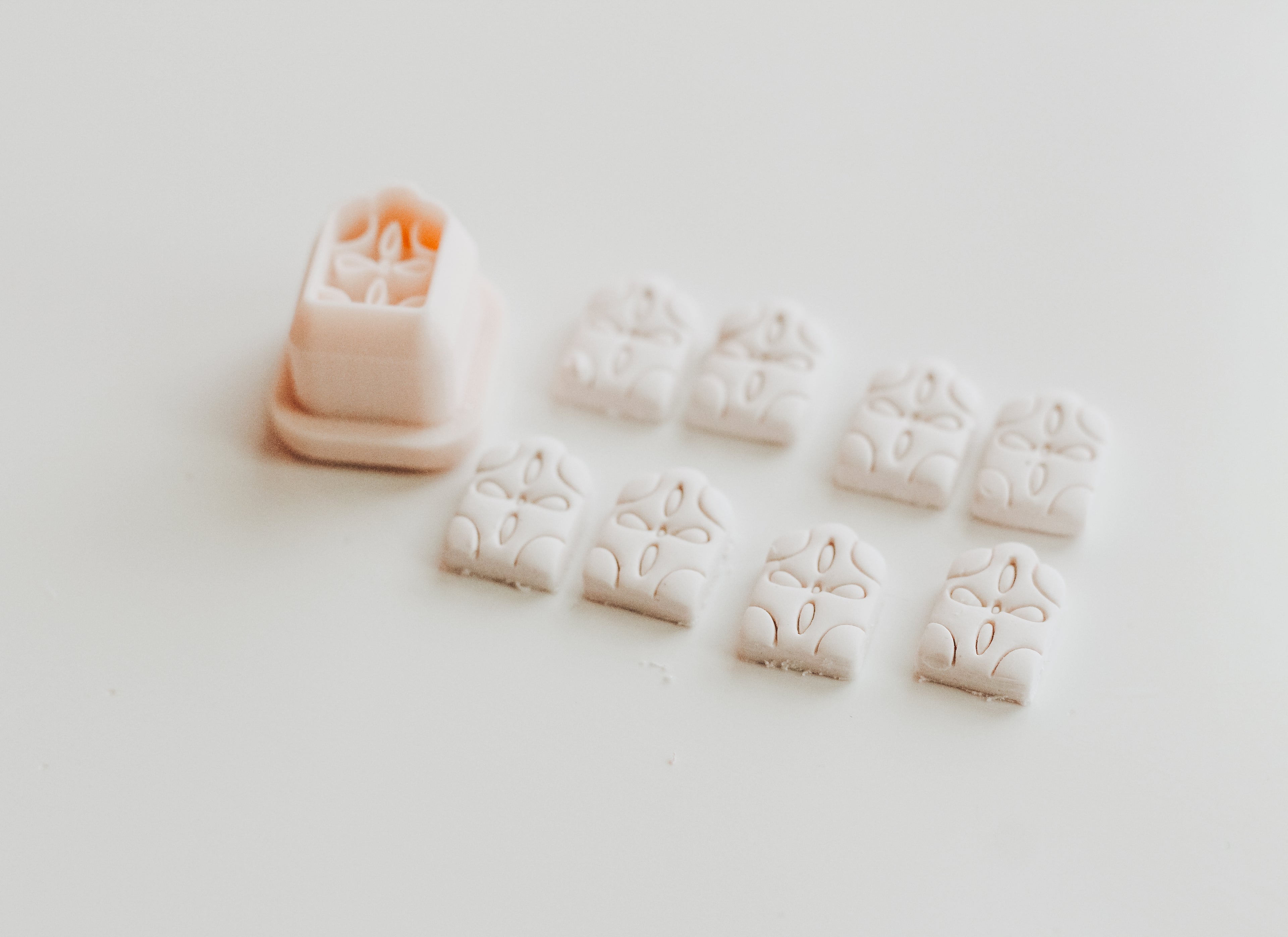 A small 3D printed arch-shaped object with a floral-inspired design with several cut out examples of the shape against a light colored background