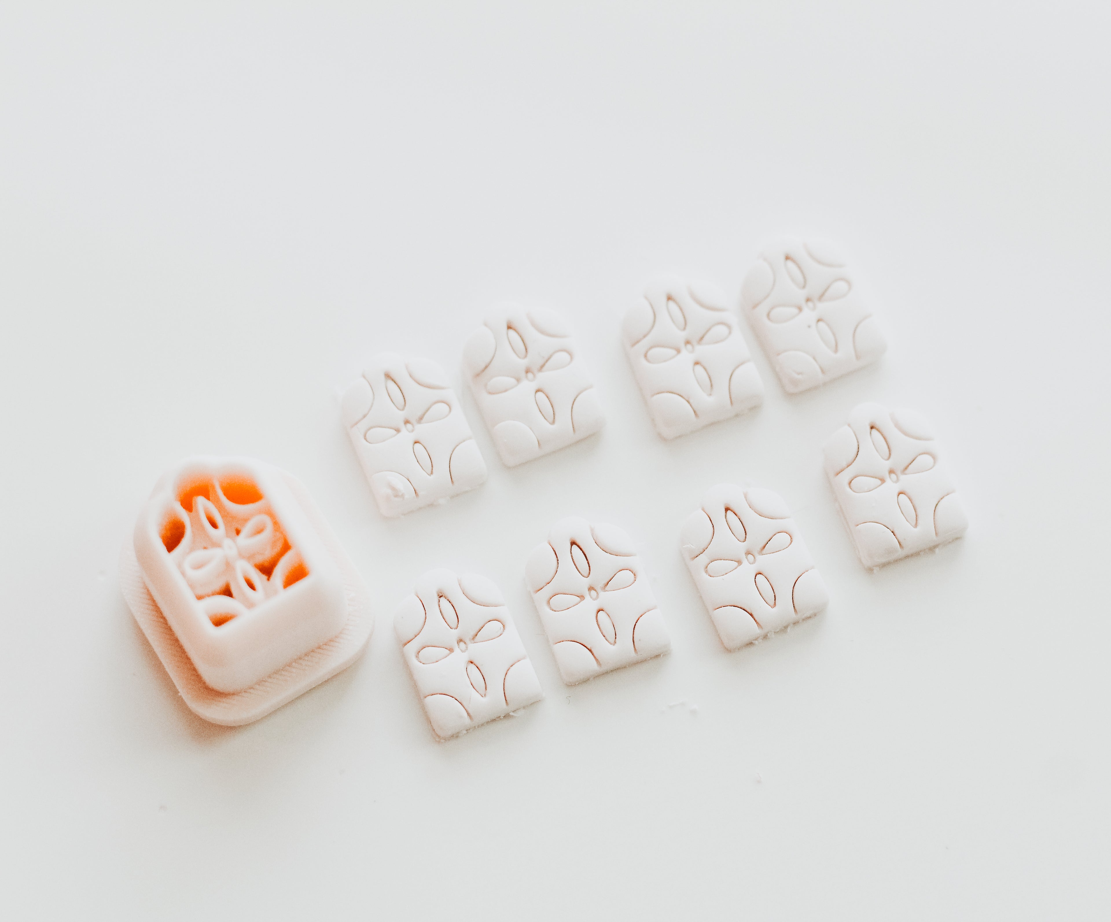 A small 3D printed arch-shaped object with a floral-inspired design with several cut out examples of the shape against a light colored background