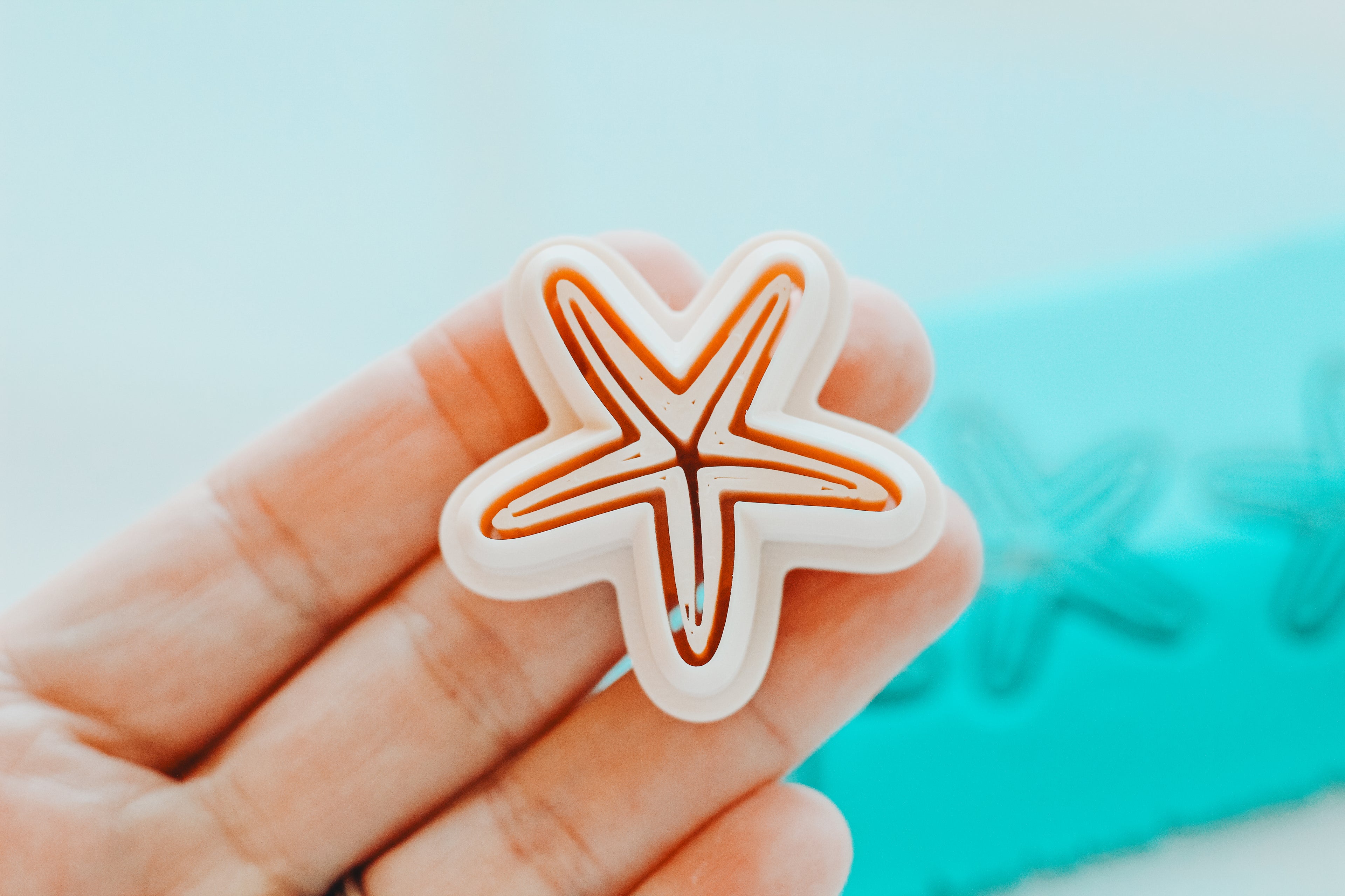 Starfish-shaped object held in a hand with a blurred blue background