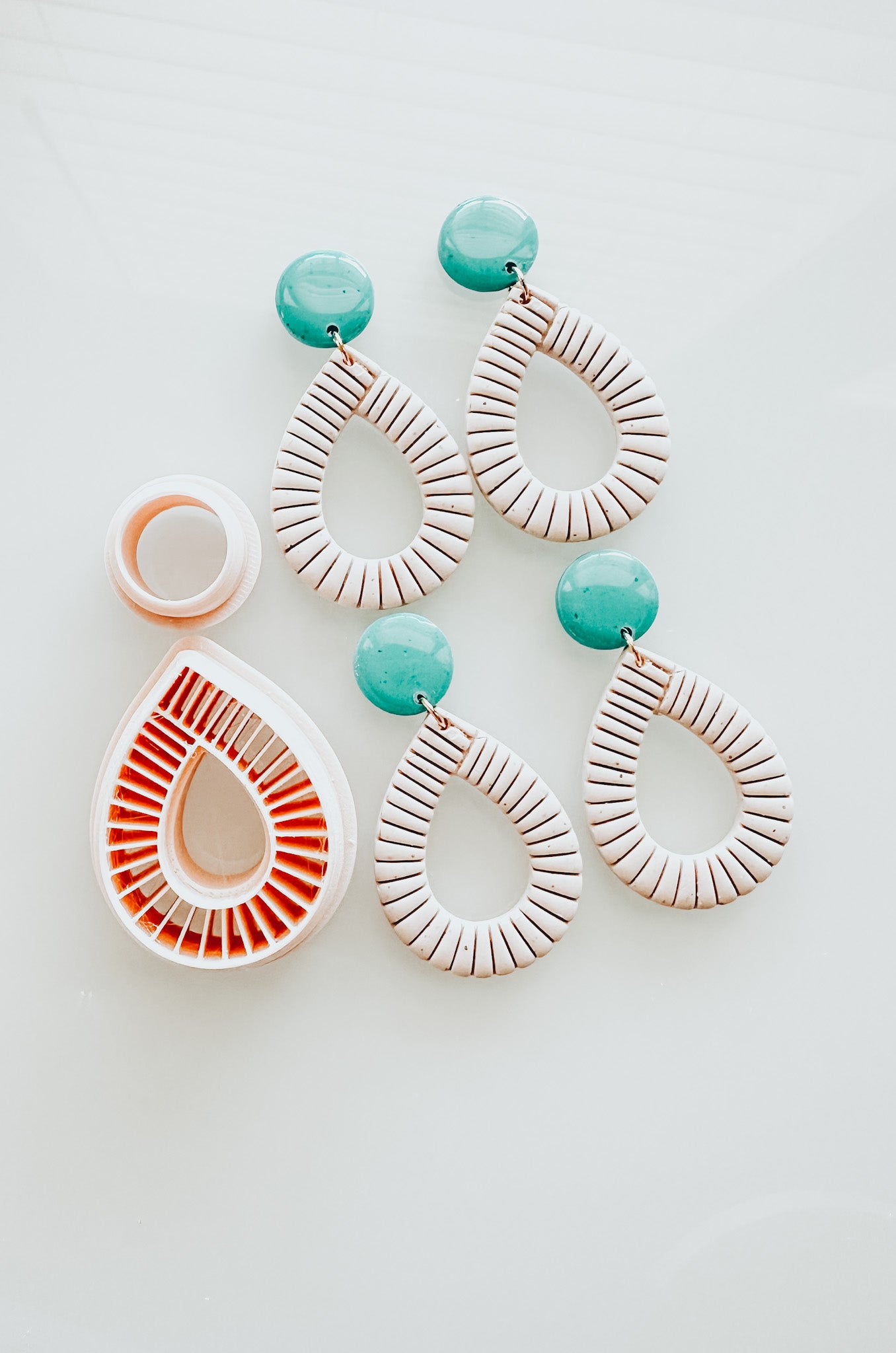 Finished set of polymer clay earrings, using a turquoise top and white hoop bottom, as well as a 3D printed clay cutter.