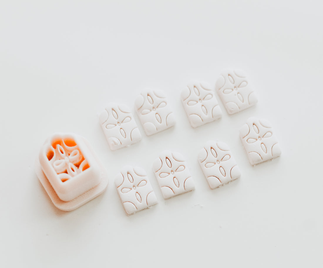 A small 3D printed arch-shaped object with a floral-inspired design with several cut out examples of the shape against a light colored background