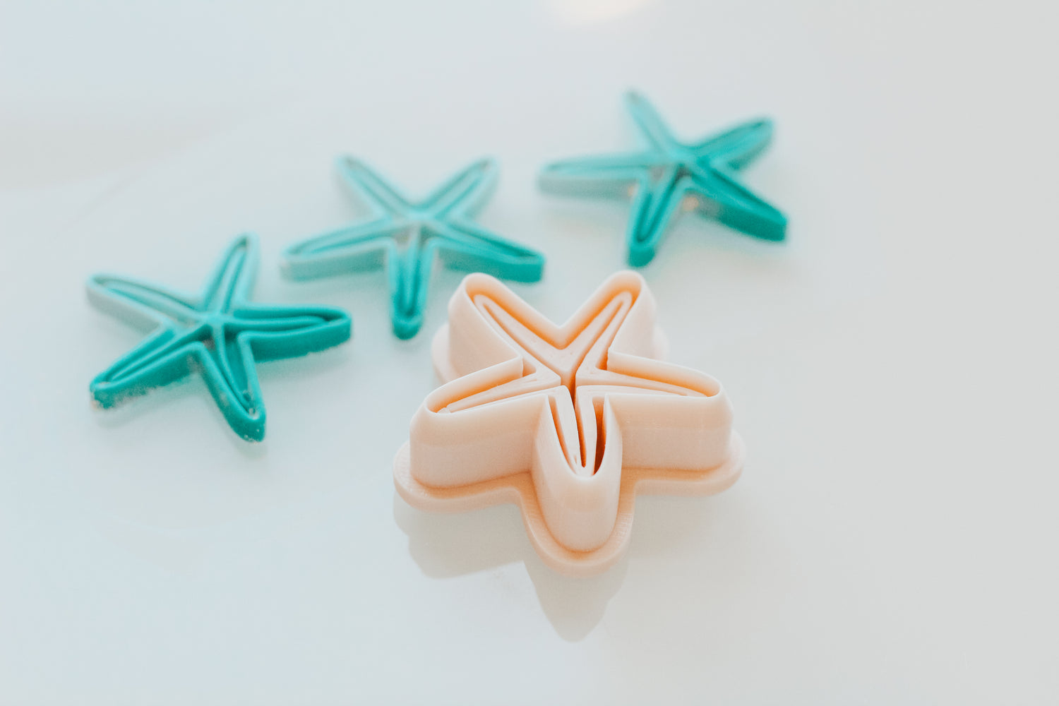 Star Fish Shape clay cutters in teal and peach on a white background